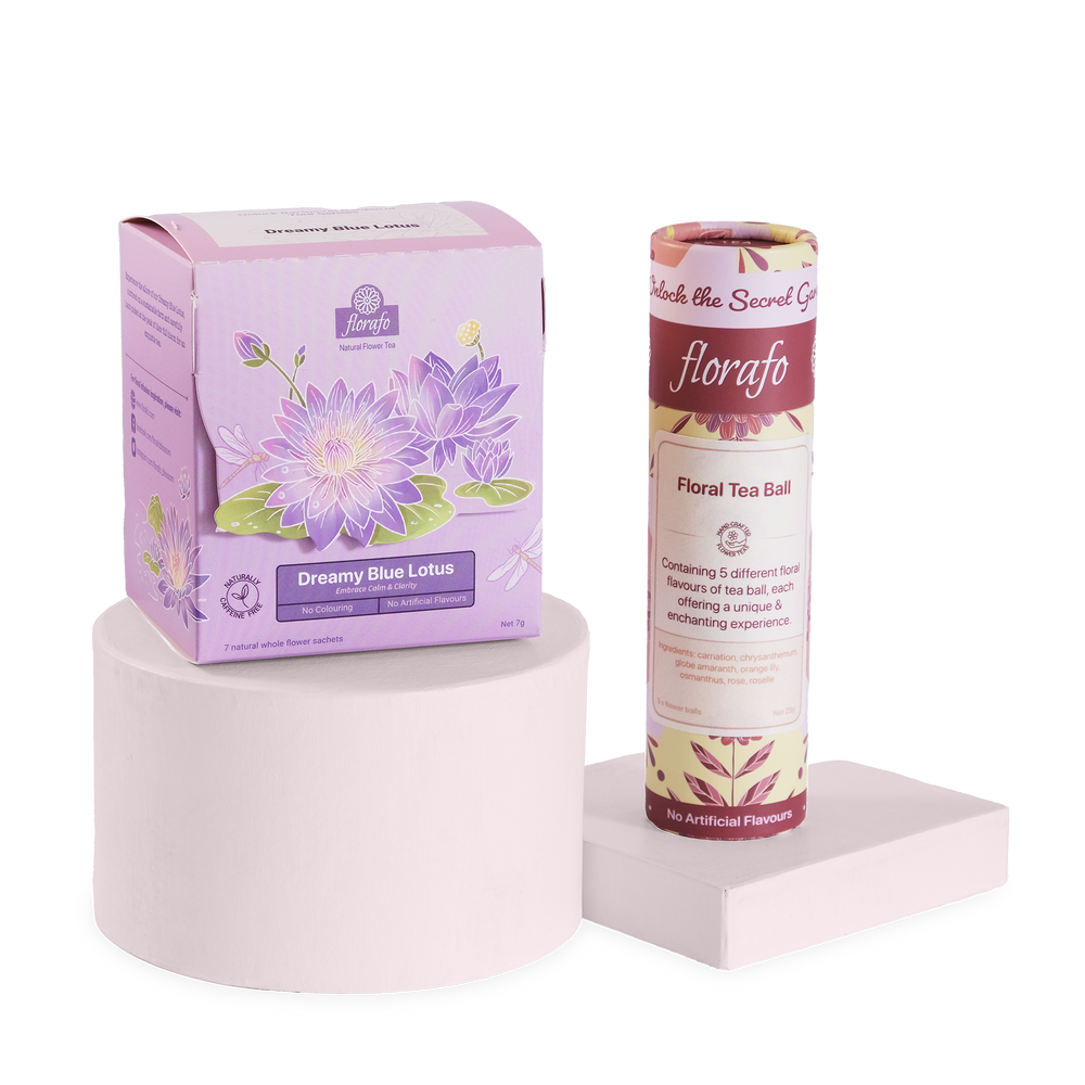 florafo bundle of a box of Dreamy Blue Lotus whole flower infusions next to a paper tube of Floral Tea Ball flower balls. The box is sitting on a pastel pink cylindrical platform and the tube is standing on a lower square pastel pink platform.